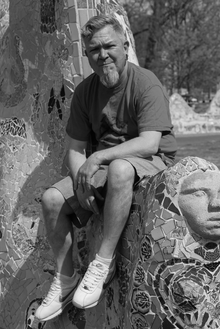 Mighty Rock seated on a mosaic sculpture, serious expression